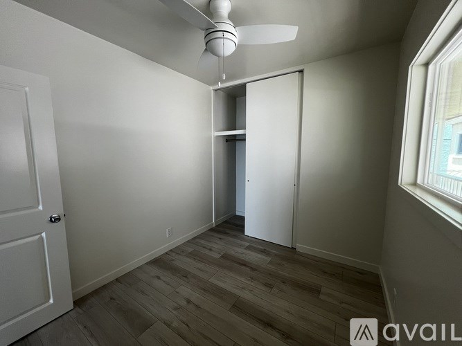 A room with a ceiling fan and a door on the left.