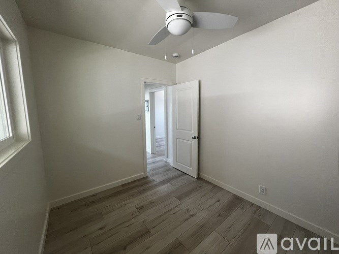 A room with a ceiling fan and wooden flooring.