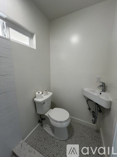 A small bathroom with a toilet, sink and a window.