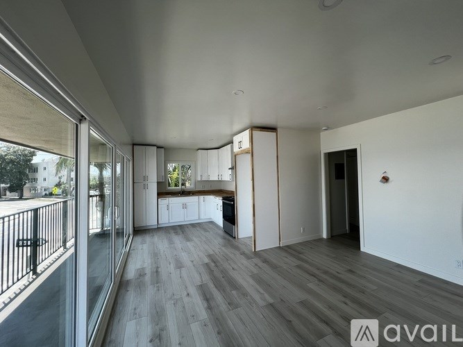 A spacious room with wooden flooring and a balcony with a railing.