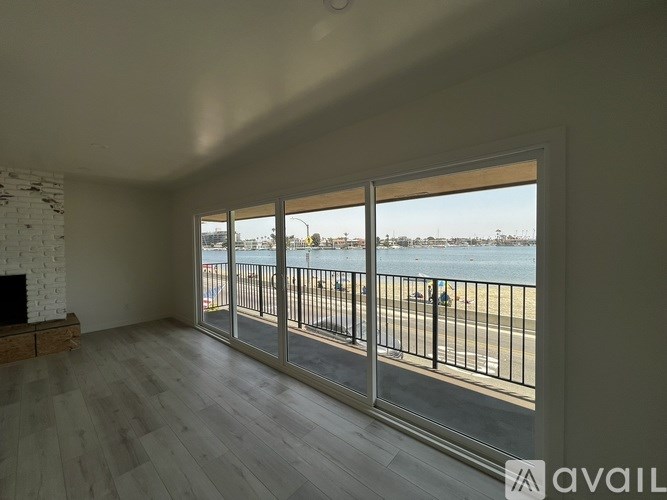 A room with a fireplace and a view of the beach through the windows.