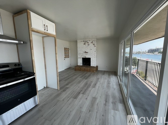 A kitchen with a stove top oven and a fireplace in a room with wooden flooring.