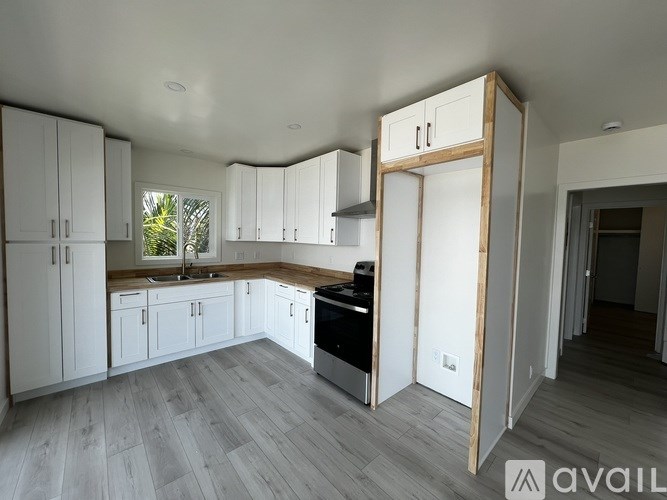A modern kitchen with white cabinets and a wooden accent wall.