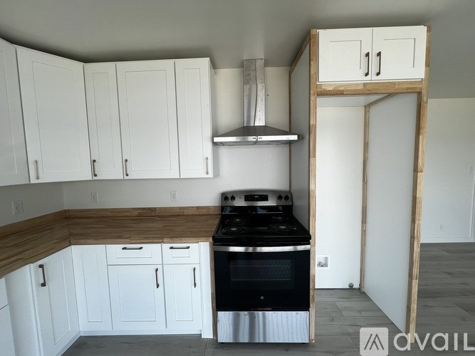 A kitchen with white cabinets and a black stove top oven.