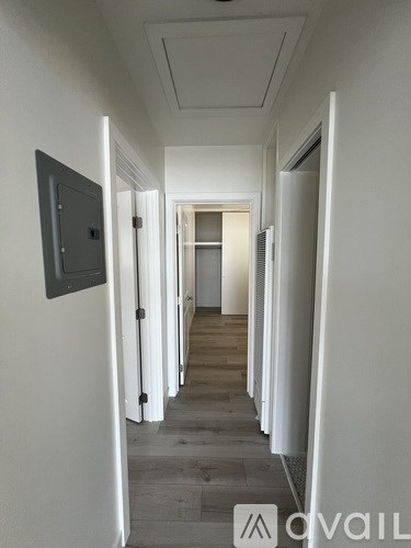 A long hallway with doors on both sides and a white wall.
