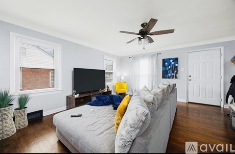 A living room with a grey couch and a ceiling fan.