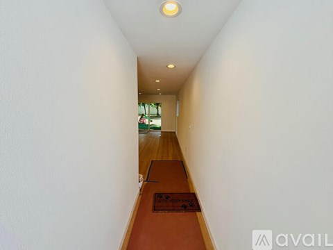 A long hallway with a brown carpet and white walls.
