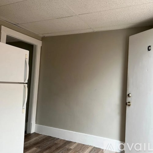 A room with a white fridge and a white door.
