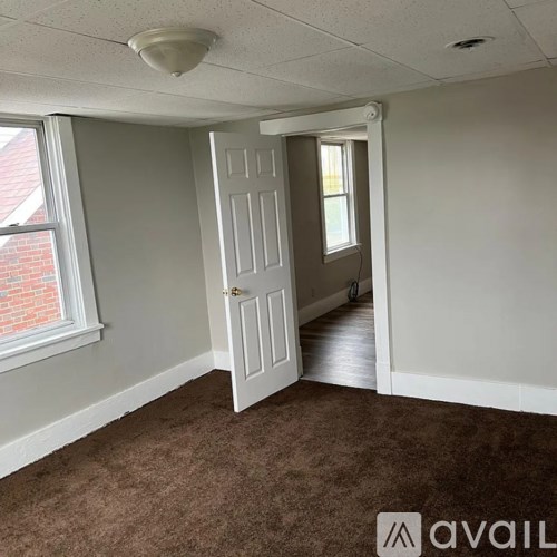 A room with a carpeted floor, a door, and a window.