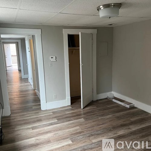 A room with a wooden floor and a door open to another room.