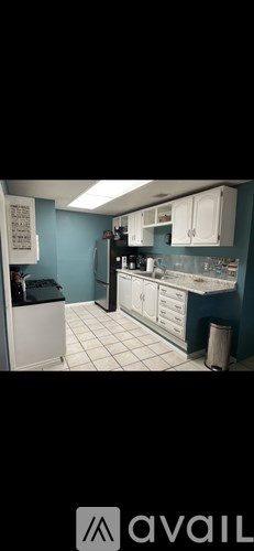 A kitchen with a white refrigerator and white cabinets.