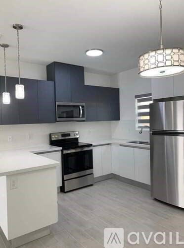 A modern kitchen with dark blue cabinets and stainless steel appliances.