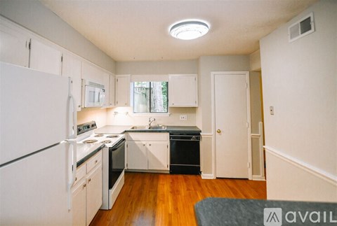 A kitchen with white appliances and wooden floors.