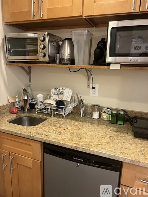 A kitchen counter with a sink, a toaster oven, and a microwave on top of it.