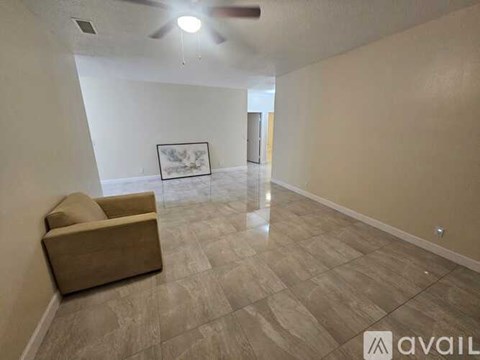 A living room with a beige couch and a ceiling fan.