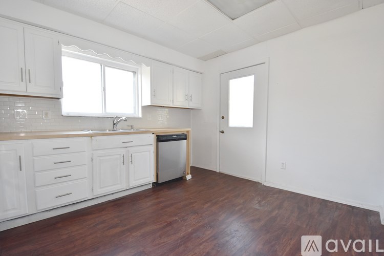A kitchen with white cabinets and a wooden floor.