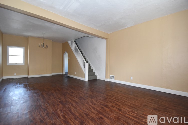 A room with wooden floors and a staircase in the background.