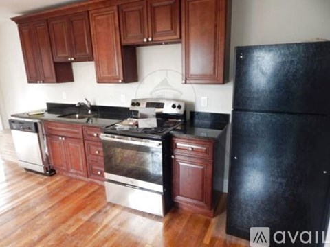 A kitchen with wooden cabinets and a black refrigerator.