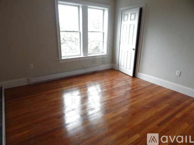 A room with wooden flooring and a door leading to another room.