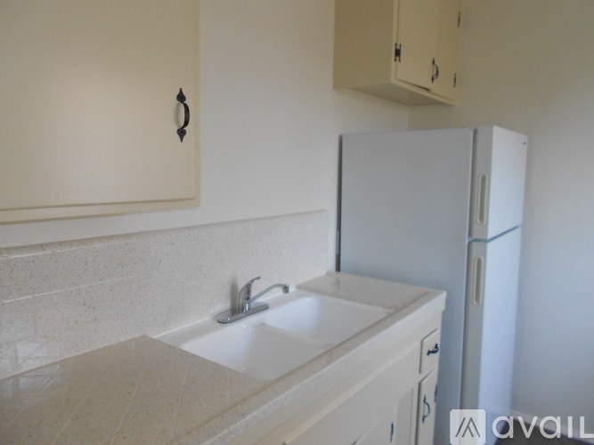 A white sink with a silver faucet is in a white counter top.