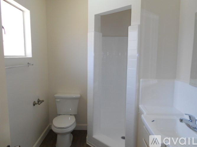 A white toilet in a small bathroom with a white sink and a white cabinet.