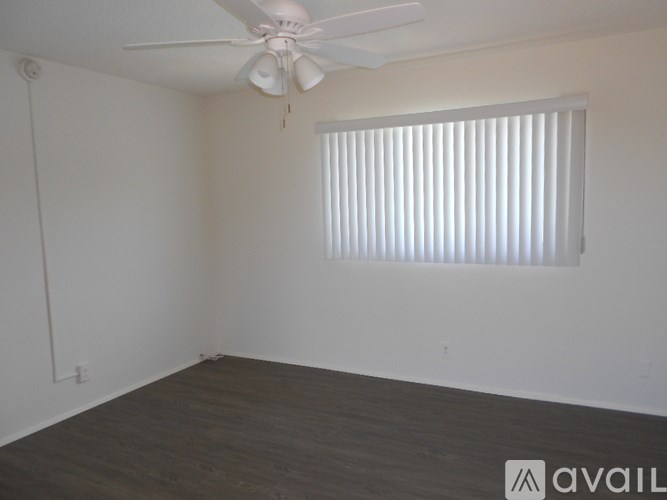 A room with a ceiling fan and a window with blinds.