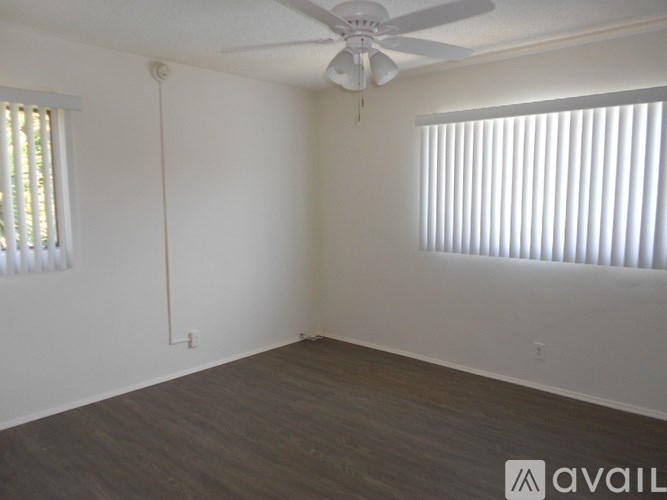 A room with a ceiling fan and a window with blinds.
