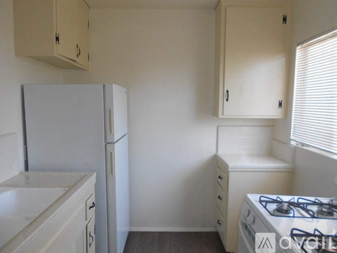 A small kitchen with a refrigerator, sink, and a stove.