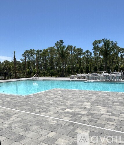 A large outdoor swimming pool surrounded by trees and lounge chairs.