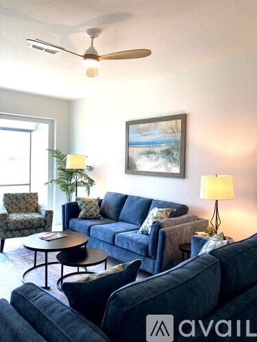 A living room with a blue couch and a painting on the wall.