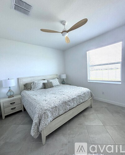 A bedroom with a bed, nightstand, and window.