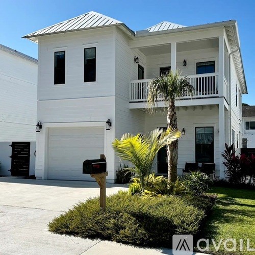 A white two-story house with a balcony and a mailbox.