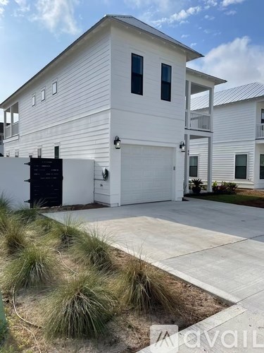 A white house with a black garage door and a driveway.