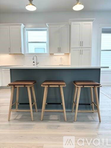 Two bar stools with wooden legs and seats are placed in front of a kitchen island.