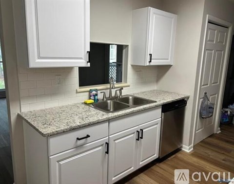 A kitchen with white cabinets and a granite countertop.