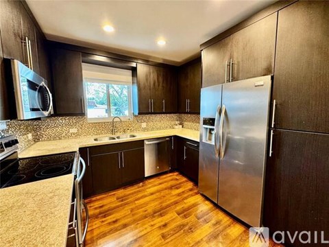 A kitchen with dark wood cabinets and a stainless steel refrigerator.