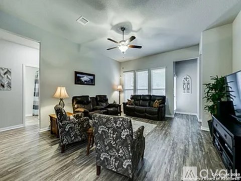 A living room with a grey sofa set and a ceiling fan.