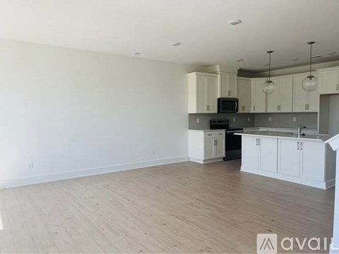 A spacious kitchen with white cabinets and a wooden floor.