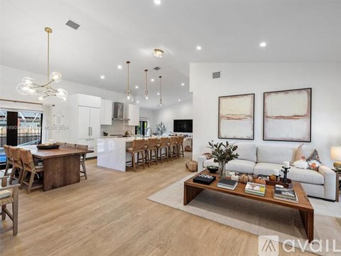 A living room with a white couch, wooden coffee table, and a dining table with chairs.