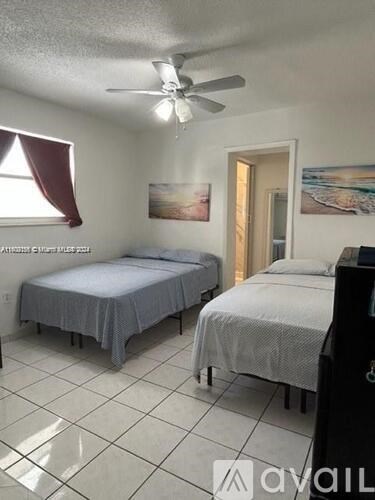A bedroom with two beds and a ceiling fan.