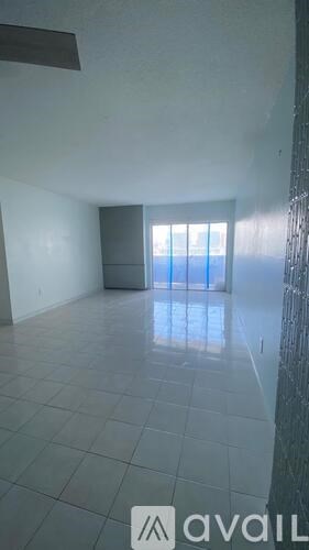 A room with a tiled floor and a glass door leading to a balcony.