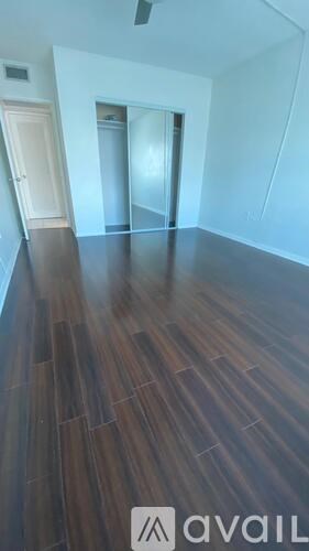 A room with a wooden floor and a door in the background.