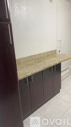 A kitchen counter with a marble top and dark brown cabinets.