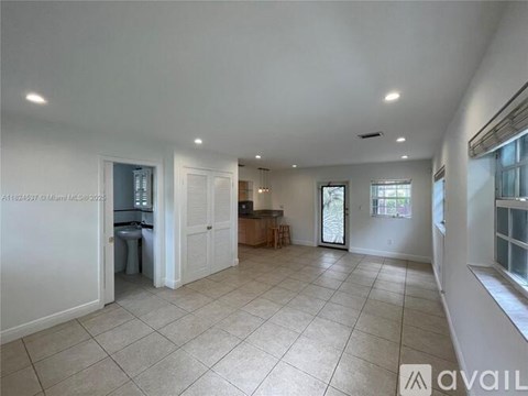 A spacious living room with a kitchen area in the background.