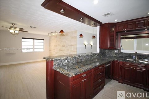 A kitchen with dark wood cabinets and a granite countertop.