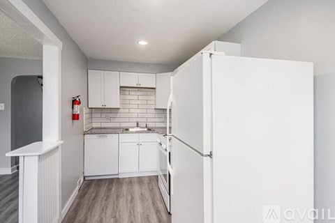 A kitchen with white cabinets and a white fridge.