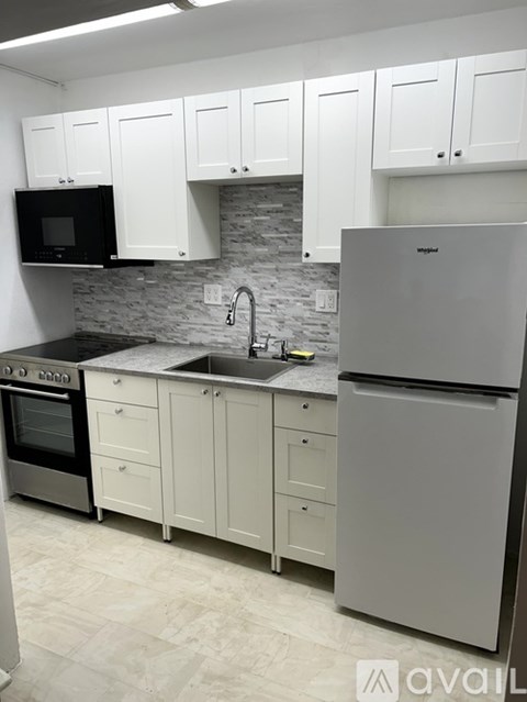 A kitchen with white cabinets and a grey fridge.