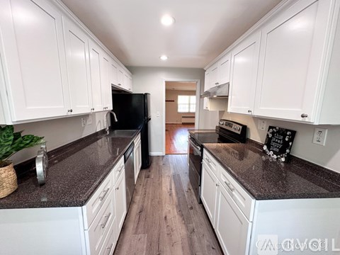A kitchen with white cabinets and black appliances.