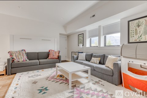 A living room with a grey couch, a white coffee table, and a rug with a star pattern.