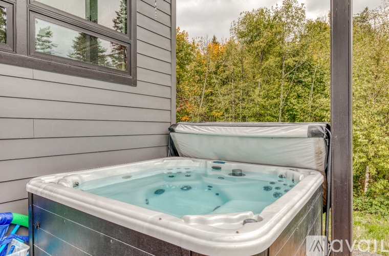 A hot tub sits on a deck next to a house.